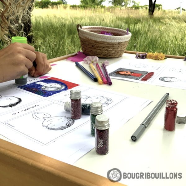 Enfant en pleine activité créative mettant en couleurs les cartes des émotions Bougribouillons (feutre, peinture, paillettes, fleurs, colle)